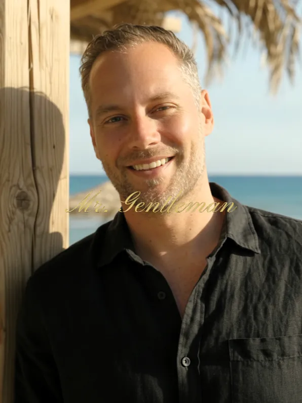 Smiling portrait of Mr. Gentleman in a black shirt at a beach bar in Lasithi, Crete