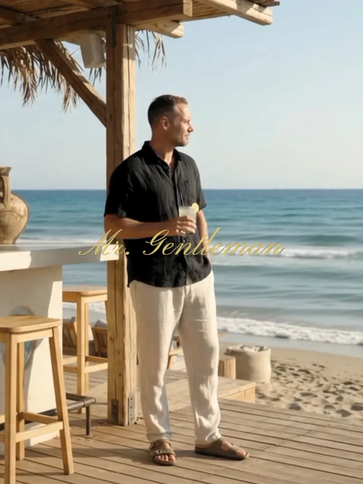 Mr. Gentleman in linen trousers and a black shirt at a beach bar in Plaka, Crete