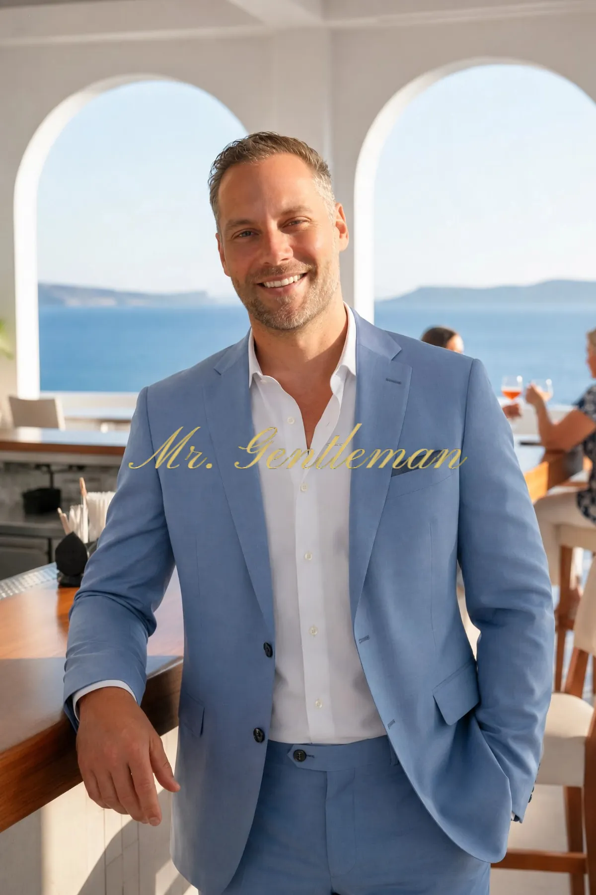 Mr. Gentleman in a light blue suit under white arches by the sea in Crete