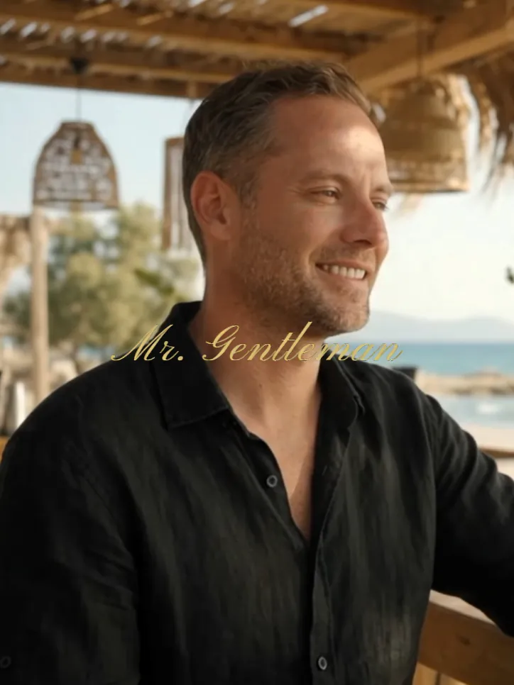 Warm smile of Mr. Gentleman in a black shirt at a beach bar in Crete